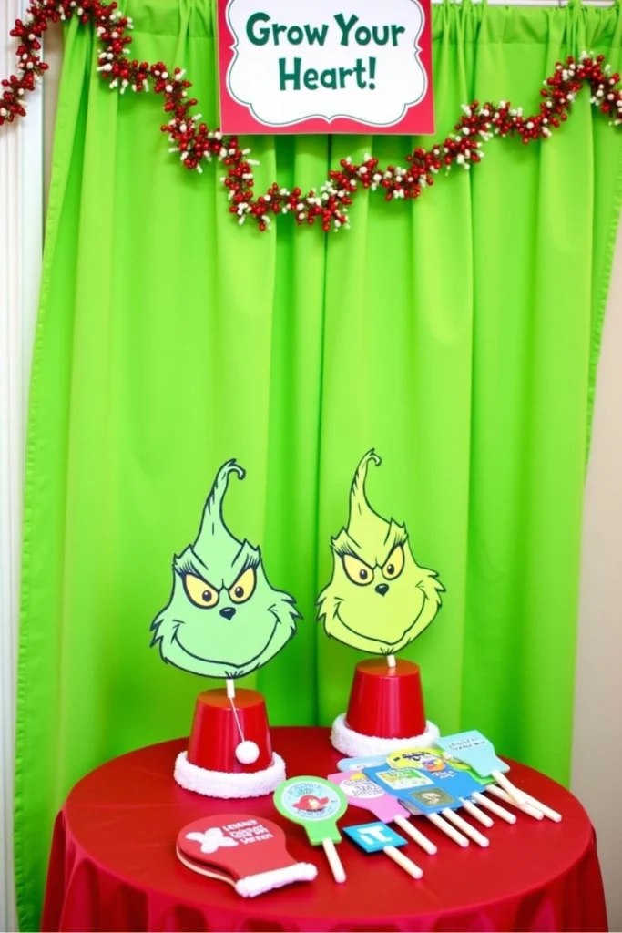 Grinch-themed Christmas photo booth corner with green curtain backdrop, “Grow Your Heart!” sign, and Grinch and Cindy Lou Who masks for party photos.